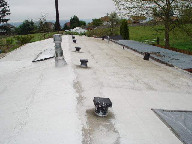 Worn low-slope roof before conversion to standing seam metal