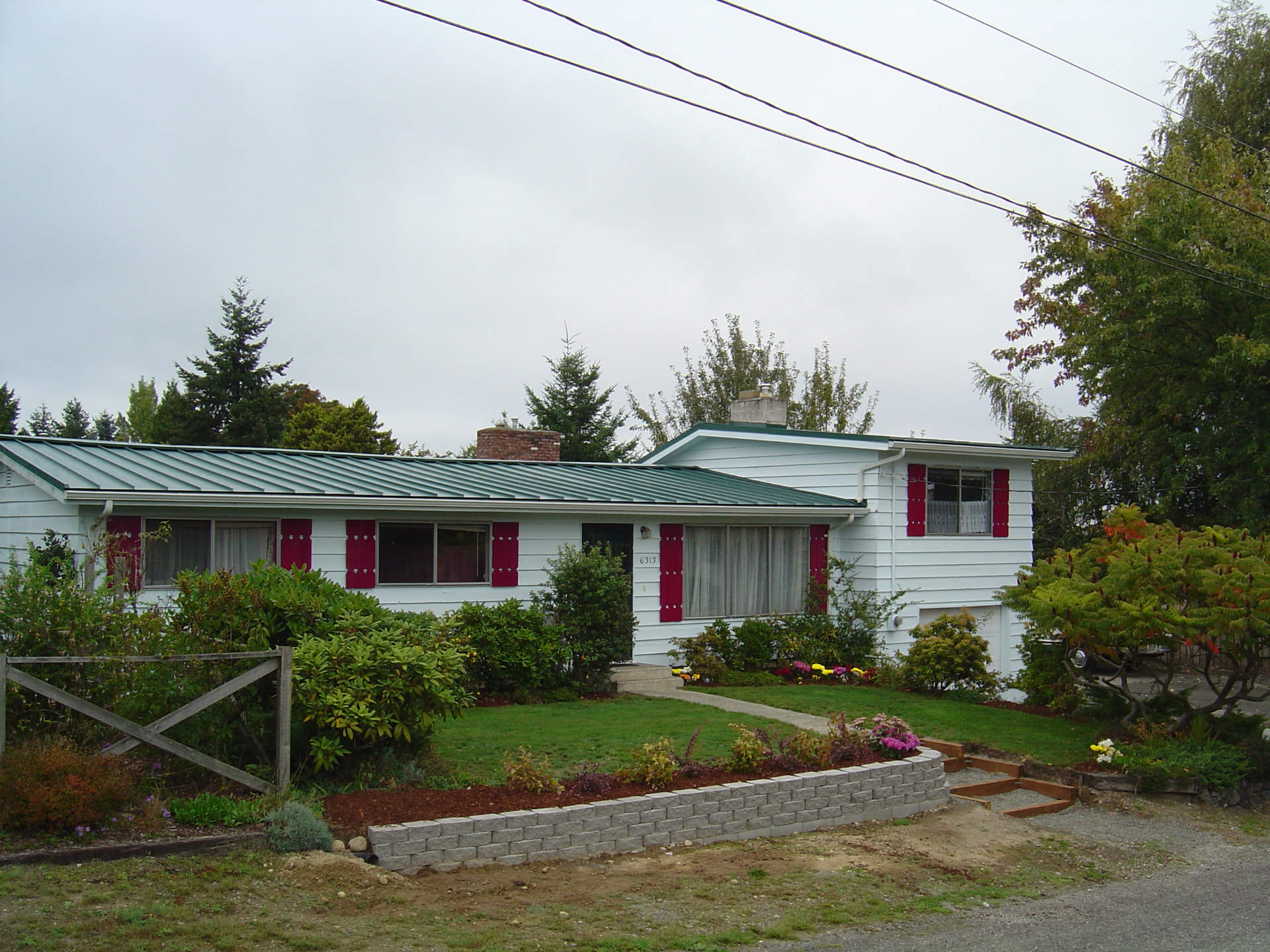 Completed green standing seam metal roof on a white Pacific Northwest home