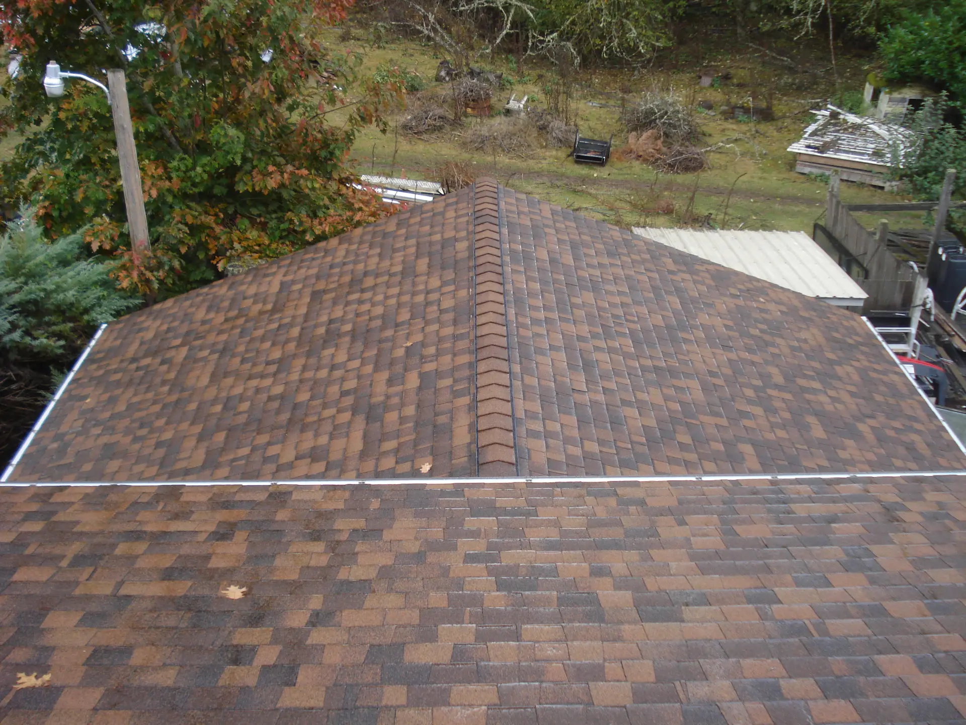 New brown architectural asphalt shingle roof with ridge cap after cedar shake tear-off